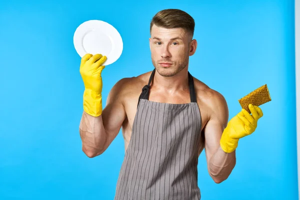 Man in apron cleaning dishwashing blue background — Stock Photo, Image