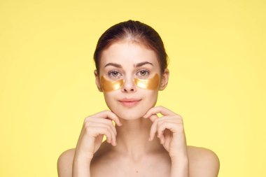 Çıplak omuzlu ve yumruklayıcı gençleştirme cilt bakımı sarı arka planlı bir kadın.
