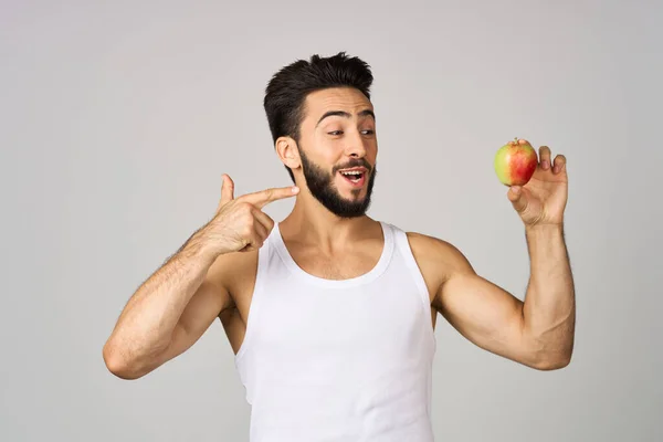 Um homem em uma t-shirt branca maçãs em mãos fruta comida saudável luz fundo — Fotografia de Stock
