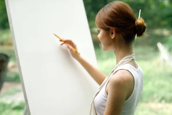 An artist in nature draws on an easel with a pencil — Stock Photo, Image