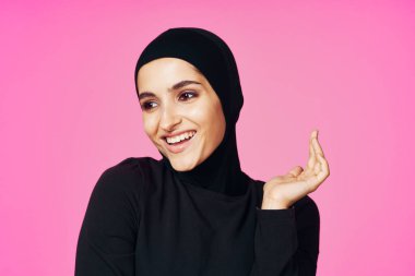 Siyah tesettürlü neşeli Müslüman kadın moda pembe arka planda