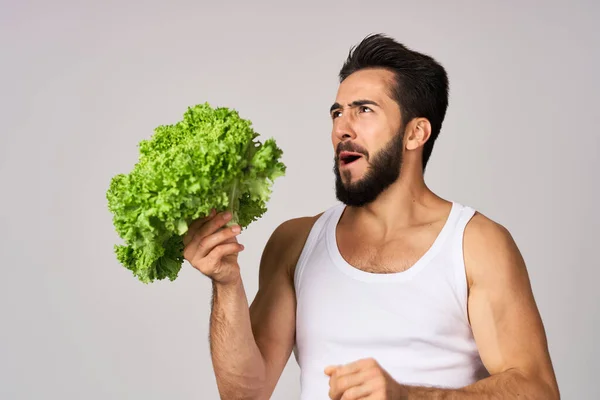 Uomo allegro in una t-shirt bianca lattuga foglie cibo sano — Foto Stock