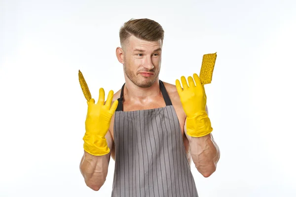 Een man in een grijs schort met rubberen handschoenen die de was schoonmaakt — Stockfoto