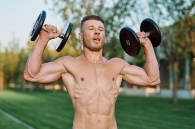 Parktaki spor egzersizinde şişirilmiş vücutlu bir sporcu.