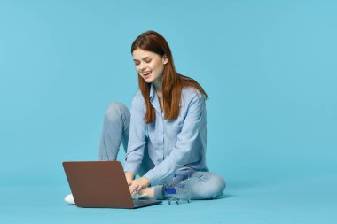 Dizüstü bilgisayarı olan bir kadın yerde oturmuş öğrenci teknolojisini öğreniyor.
