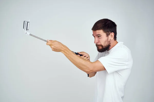 Man met baard in wit t-shirt selfie stick foto technologie — Stockfoto