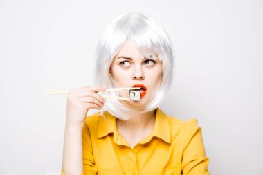 Beyaz peruklu güzel bir kadın ve Japon yemek çubuklarıyla suşi.