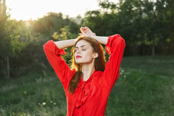 Mulher atraente em vestido vermelho posando na natureza grama verde — Fotografia de Stock