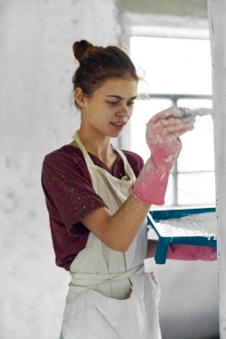 Beyaz önlüklü ev dekorasyonu yapan kadın ressam.