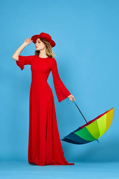 Donna in abito rosso multicolore ombrello sfondo blu — Foto Stock