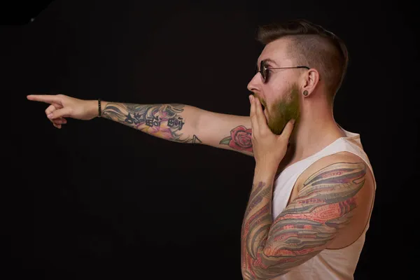 Бородатый мужчина в белой футболке с татуировками на руках, позирующий хулиганом — стоковое фото