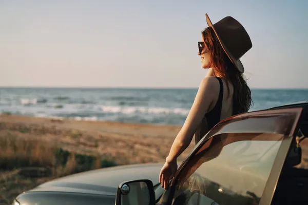 Hübsche Frau mit Sonnenbrille in der Nähe des Autos am Strand — Stockfoto