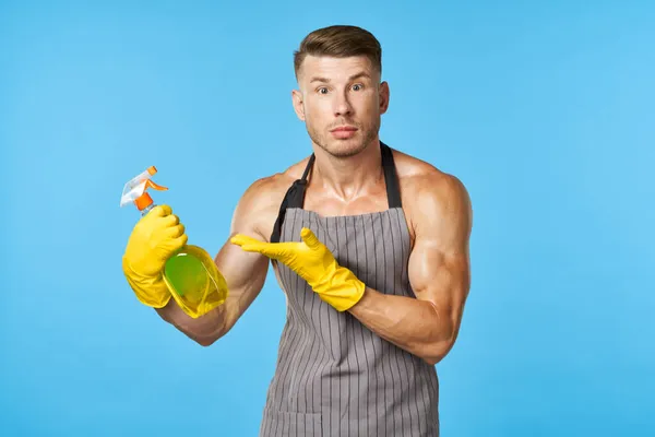 Een man met een opgepompt lichaam in schorten schoonmaakmiddel — Stockfoto