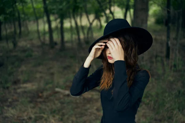 Mulher bruxa de chapéu preto na floresta posando fantasia — Fotografia de Stock