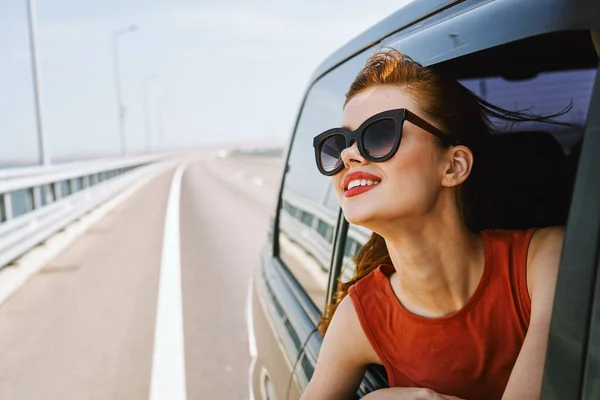 Frau blickt mit Sonnenbrille aus Autofenster — Stockfoto