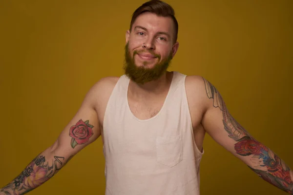 Cheerful bearded man in a white T-shirt with hooligan tattoos on his arms — Stock Photo, Image