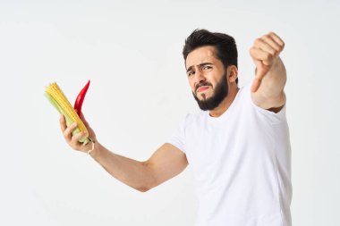 Elinde sebzelerle sakallı bir adam. Sıcak biberli mısır.