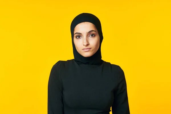 Kvinna i muslimska kläder poserar islam gul bakgrund — Stockfoto