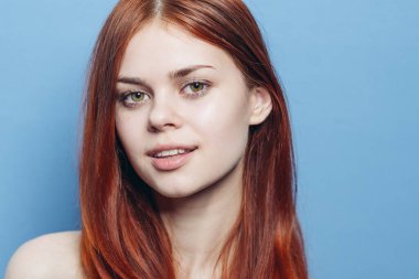 Çıplak omuzlu çekici bir kadın. Kızıl, yakın plan, mavi arka plan.