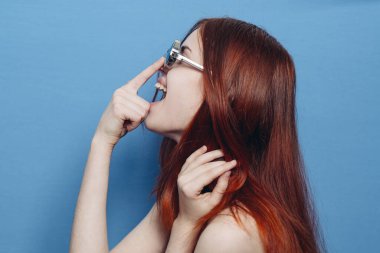 Çıplak omuzlu, gözlüklü, mavi arka planlı çekici bir kadın.