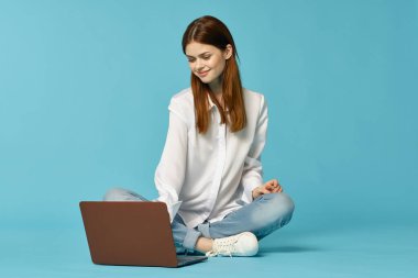 Dizüstü bilgisayarı olan bir kadın yerde oturup internet teknolojisi öğreniyor.