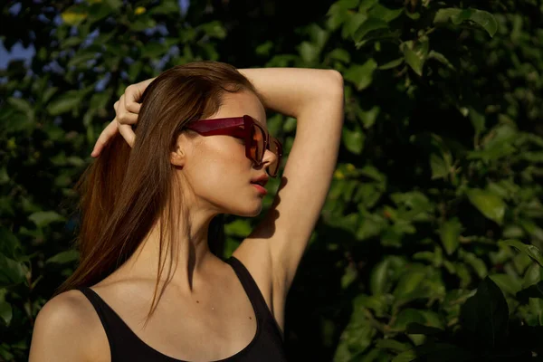 Attraktive Frau posiert vor dem Hintergrund der grünen Blätter der Natur — Stockfoto