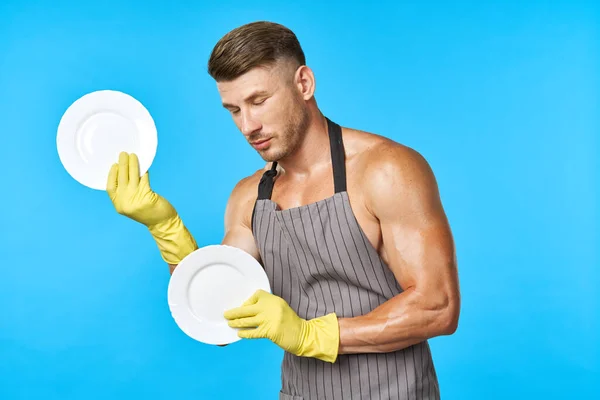 Mężczyzna w gumowych żółtych rękawiczkach z talerzem w ręku zmywa naczynia — Zdjęcie stockowe