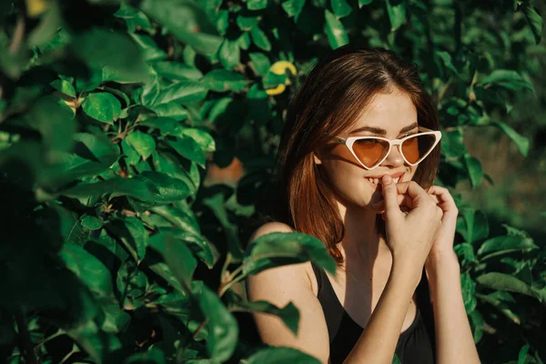 Sonriente mujer usando gafas de sol verde hojas naturaleza moda — Foto de Stock