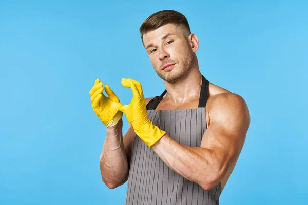 Man in schort met opgepompt lichaam rubber handschoenen schoonmaken blauwe achtergrond — Stockfoto