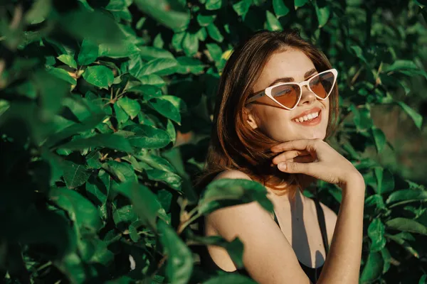 Sonriente mujer usando gafas de sol verde hojas naturaleza moda — Foto de Stock