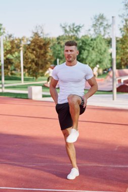 Atletik erkekler yazın spor sahasında egzersiz yapıyorlar.