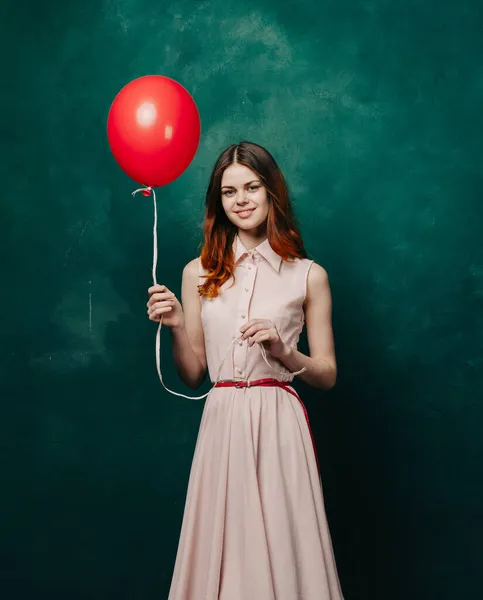 Mooie vrouw in jurk rode ballon vakantie groene achtergrond — Stockfoto