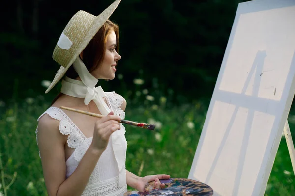 Beyaz elbiseli kadın doğa sehpasında bir resim çiziyor. — Stok fotoğraf