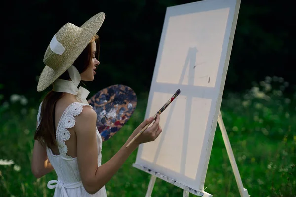 Woman in white dress paints a picture on nature easel — Stock Photo, Image