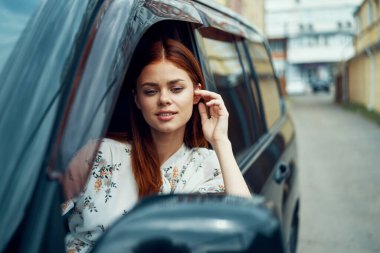 Arabayla gezen neşeli kadın pencereden dışarı bakar.