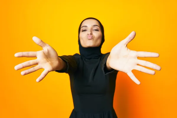 Bonita mujer en negro hijab posando mano gesto amarillo fondo — Foto de Stock