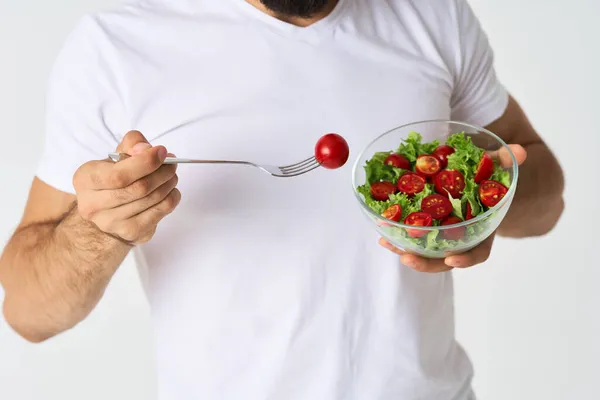 Un uomo in una t-shirt bianca in un piatto con insalata uno spuntino cibo sano — Foto Stock