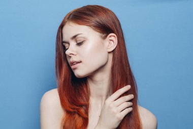 Çıplak omuzlu bir kadın. Kızıl saçlı, mavi arkaplan.