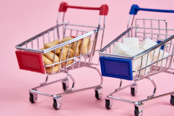 Kleine winkelwagentjes supermarkt winkelen roze achtergrond — Stockfoto