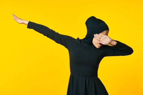 Femme musulmane en hijab noir geste avec ses mains fond jaune — Photo