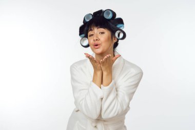 Beyaz önlüklü bir ev hanımı. Kafasında duygu bigudileri var. Ev işi.