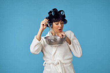 Beyaz önlüklü ev hanımı, mavi arka planı temizliyor.