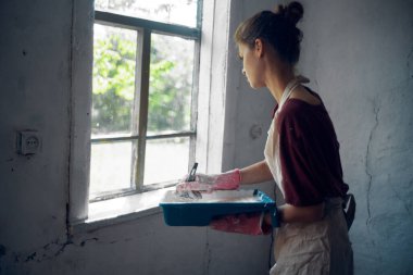 Önlüklü kadın, evin içini boyuyor.