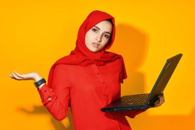 Kırmızı tesettür bilgisayar işindeki kadın sarı arkaplan öğreniyor