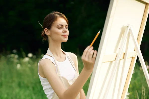 Mujer artista pinta un cuadro cerca caballete al aire libre paisaje creativo — Foto de Stock
