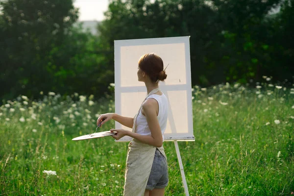 Женщина-художник на открытом воздухе с палитрой красок рисует картину — стоковое фото