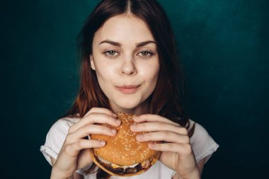 Hamburgerli neşeli kadın fast food yiyor.