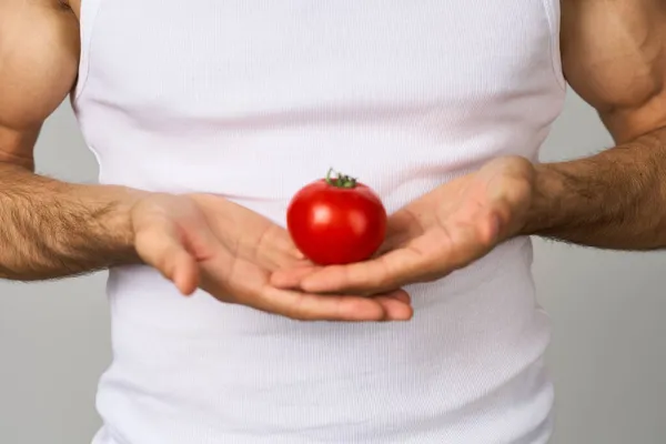 Un hombre en una camiseta blanca tomates en la mano verduras frescas salud aislado fondo —  Fotos de Stock
