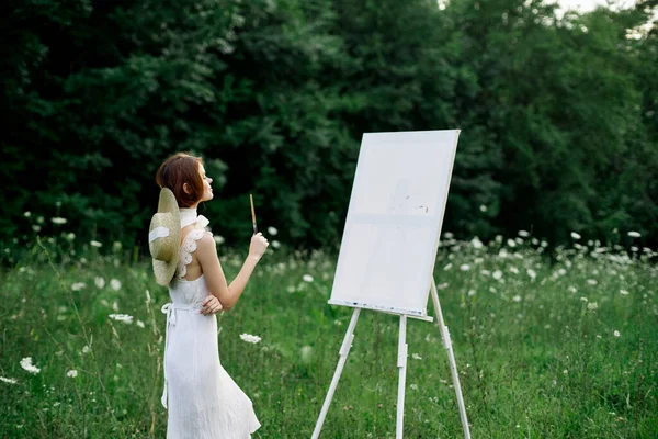 Женщина в белом платье рисует картину на открытом воздухе — стоковое фото