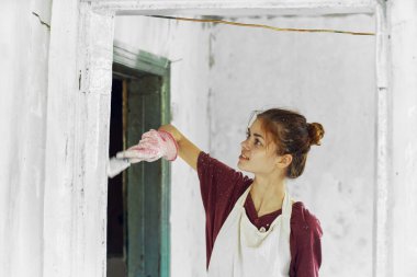 Beyaz önlüklü ev dekorasyonu yapan neşeli kadın ressam.